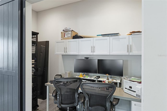 office with wood-type flooring and built in desk