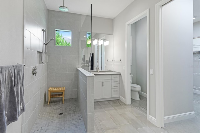 bathroom featuring tiled shower, vanity, toilet, and tile patterned floors