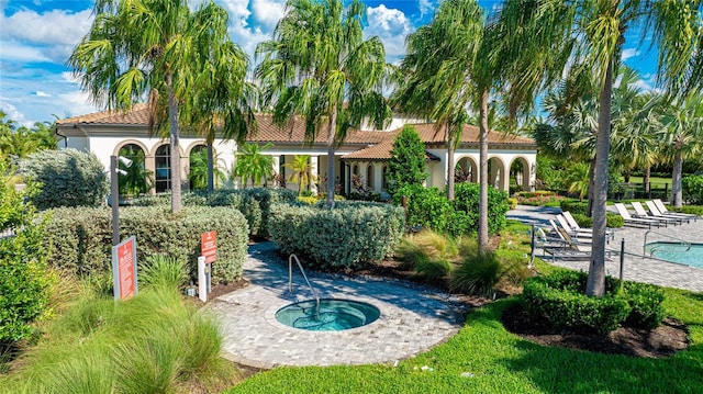 rear view of property with a community hot tub and a patio