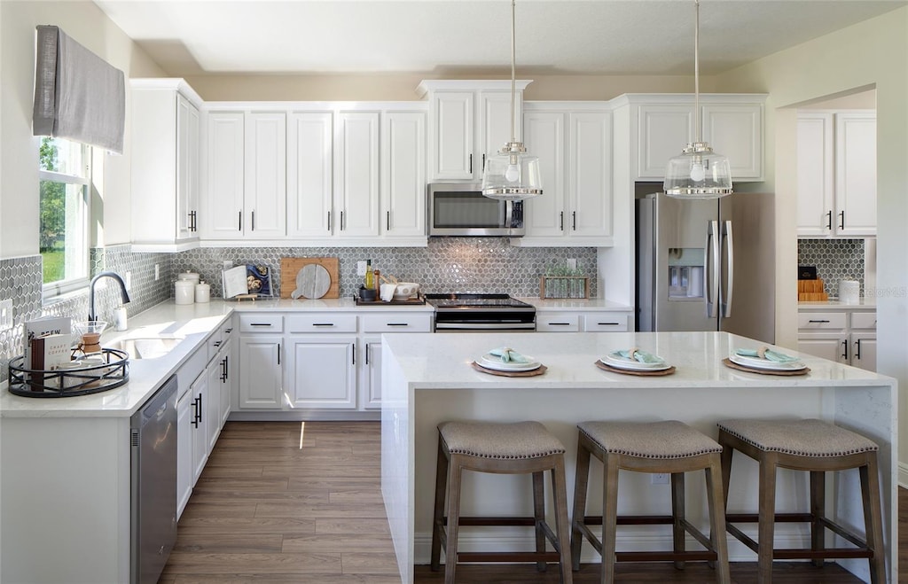 kitchen with white cabinets, appliances with stainless steel finishes, backsplash, and a center island