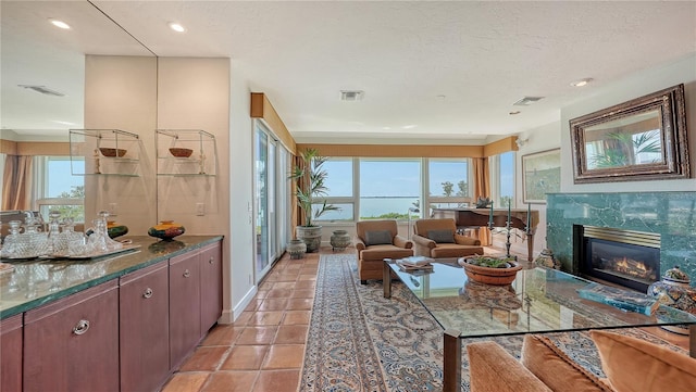 living room featuring a wealth of natural light, a high end fireplace, and a textured ceiling