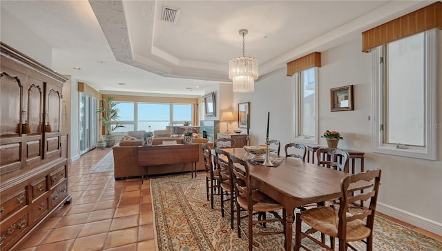 tiled dining space featuring a tray ceiling and an inviting chandelier