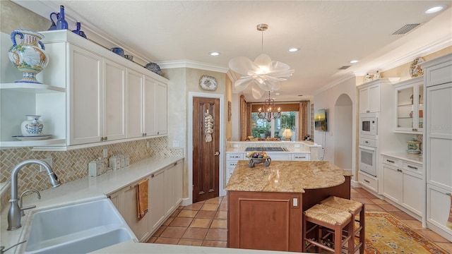 kitchen featuring sink, hanging light fixtures, white appliances, a chandelier, and a kitchen island