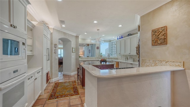 kitchen featuring white cabinetry, kitchen peninsula, white appliances, and a healthy amount of sunlight