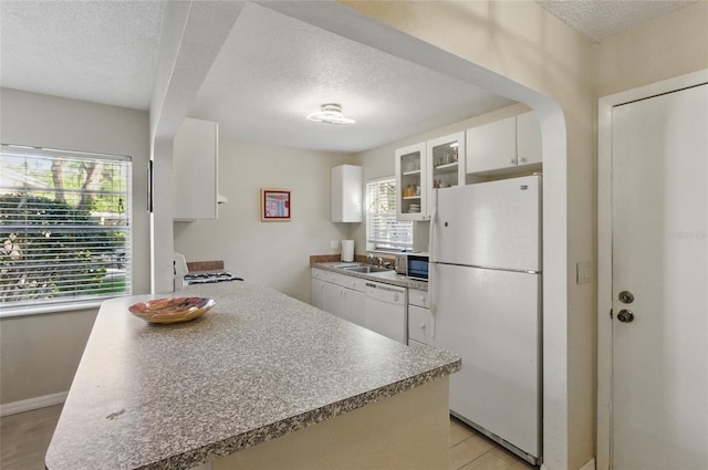 5071 Village Gardens Dr Unit 5, Sarasota, FL 34234 - kitchen with white appliances, a textured ceiling, white cabinetry, and glass insert cabinets