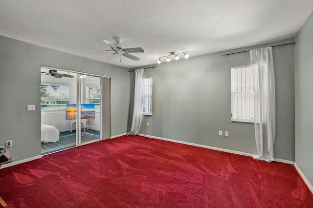 empty room with ceiling fan, a textured ceiling, carpet flooring, and track lighting