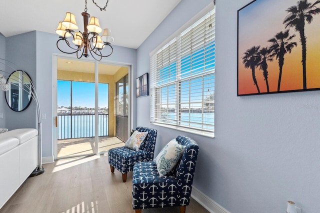 living area featuring light hardwood / wood-style flooring, a chandelier, and a water view