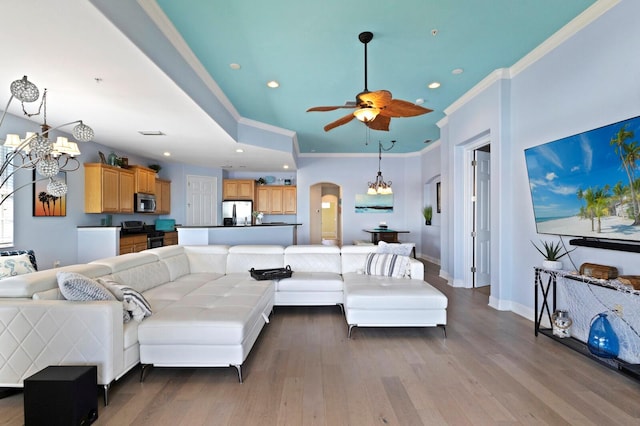 living room with ceiling fan with notable chandelier, ornamental molding, and hardwood / wood-style floors