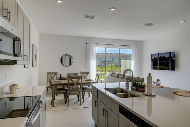 kitchen featuring appliances with stainless steel finishes, sink, light tile patterned floors, and gray cabinets