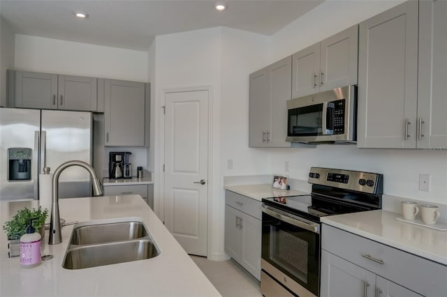 kitchen featuring gray cabinetry, appliances with stainless steel finishes, light tile patterned floors, and sink