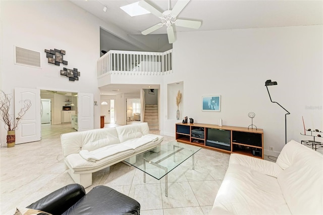 living room featuring ceiling fan, high vaulted ceiling, and a skylight