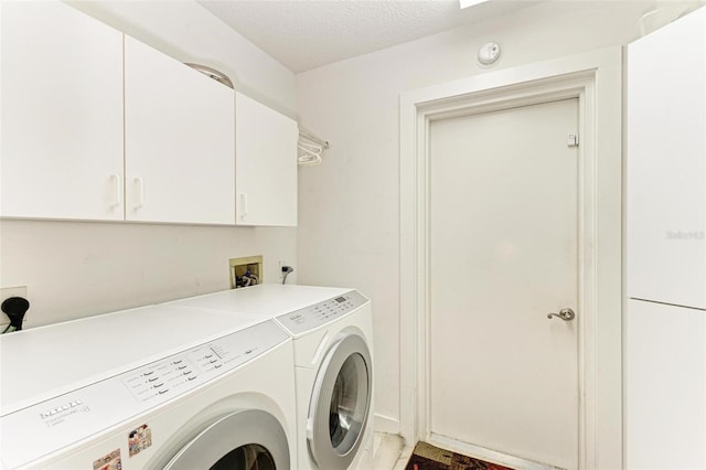 laundry area with cabinets, a textured ceiling, and washer and clothes dryer