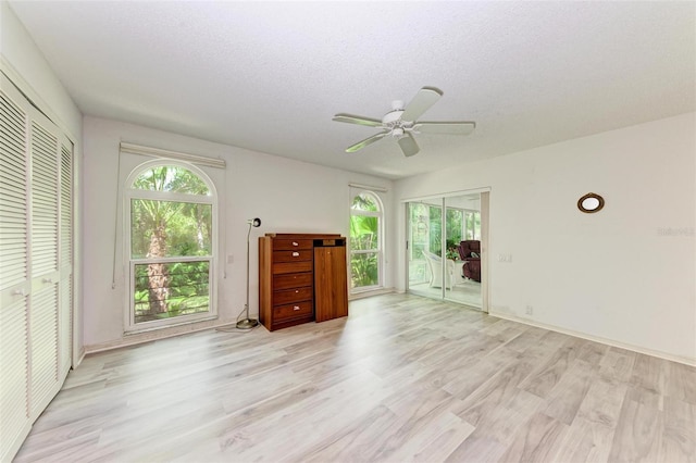 empty room with ceiling fan, a textured ceiling, and light wood-type flooring