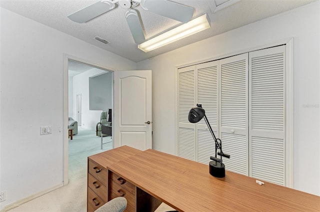 office area with light carpet, ceiling fan, and a textured ceiling