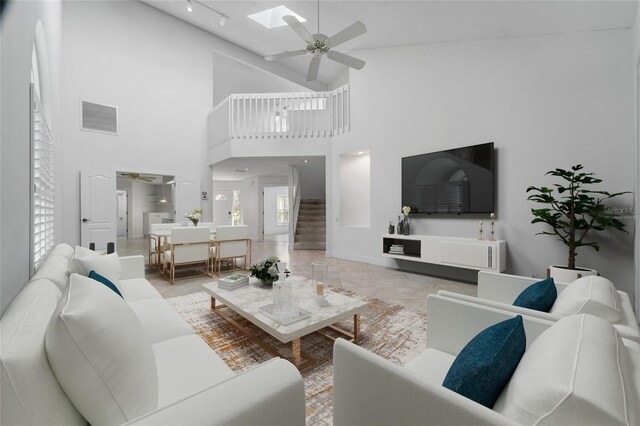 living area with visible vents, a skylight, marble finish floor, stairway, and a ceiling fan