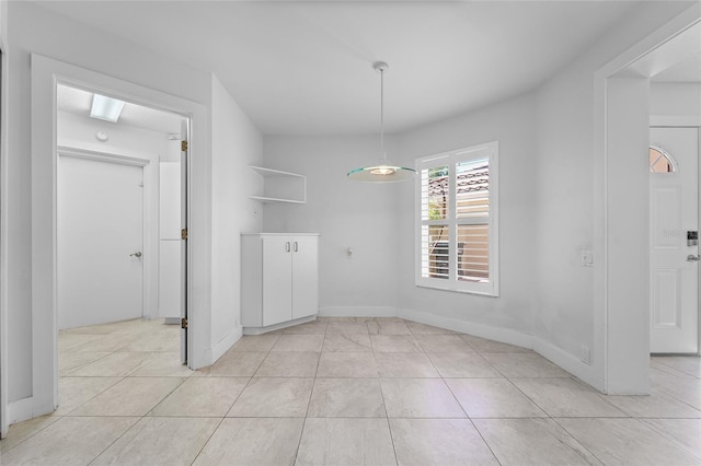 unfurnished dining area featuring baseboards and light tile patterned floors
