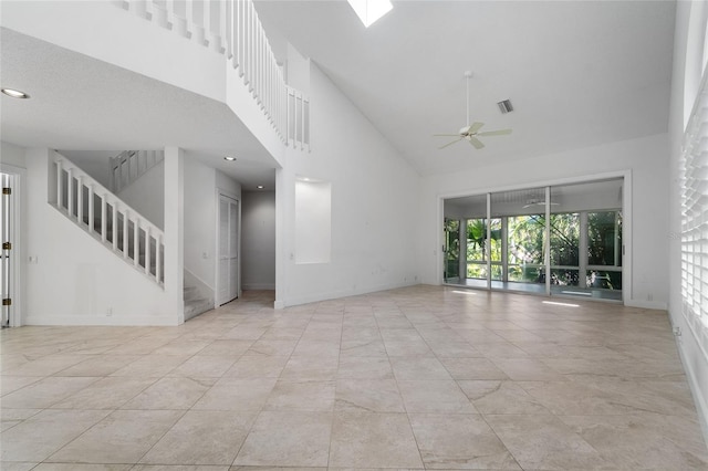 spare room with stairs, baseboards, a towering ceiling, ceiling fan, and visible vents