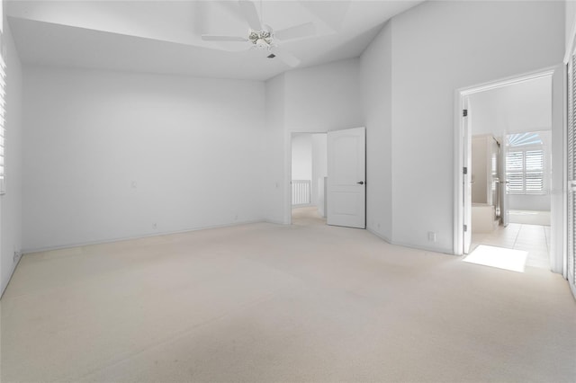 unfurnished bedroom featuring a high ceiling, light colored carpet, and ceiling fan