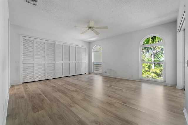 unfurnished bedroom featuring light wood-style flooring, a textured ceiling, ceiling fan, and visible vents