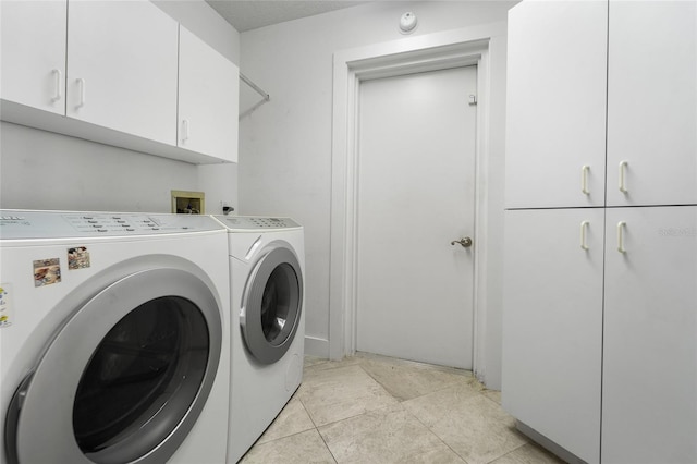 laundry area featuring light tile patterned floors, cabinet space, and washing machine and dryer