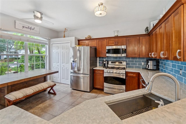 kitchen featuring sink, decorative backsplash, appliances with stainless steel finishes, light tile patterned floors, and ceiling fan