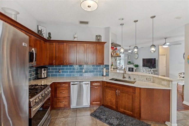 kitchen with backsplash, kitchen peninsula, stainless steel appliances, decorative light fixtures, and sink