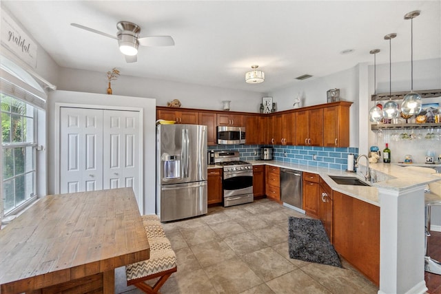 kitchen featuring decorative backsplash, kitchen peninsula, pendant lighting, stainless steel appliances, and sink