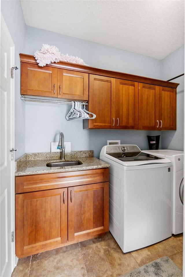 laundry room featuring cabinets, a textured ceiling, sink, and washer and dryer