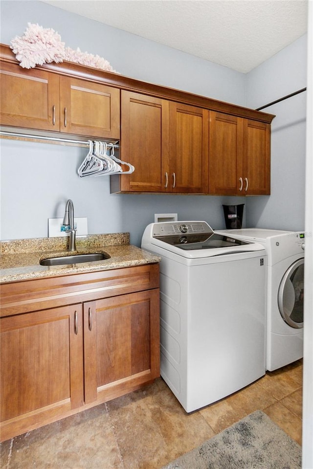 laundry room with cabinets, a textured ceiling, sink, washing machine and clothes dryer, and light tile patterned floors