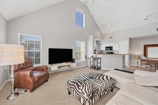 living room with light carpet, plenty of natural light, track lighting, and high vaulted ceiling