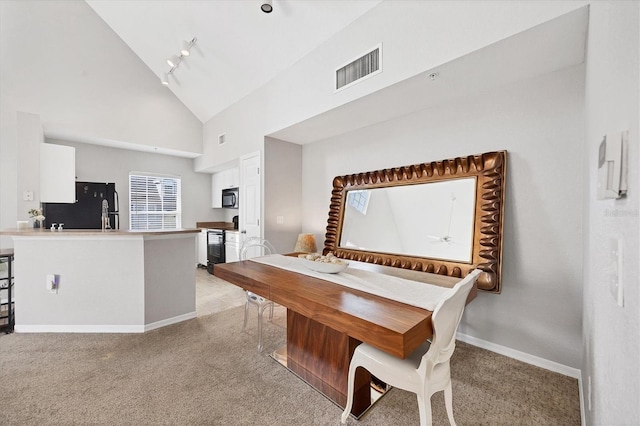 carpeted dining space featuring track lighting and high vaulted ceiling