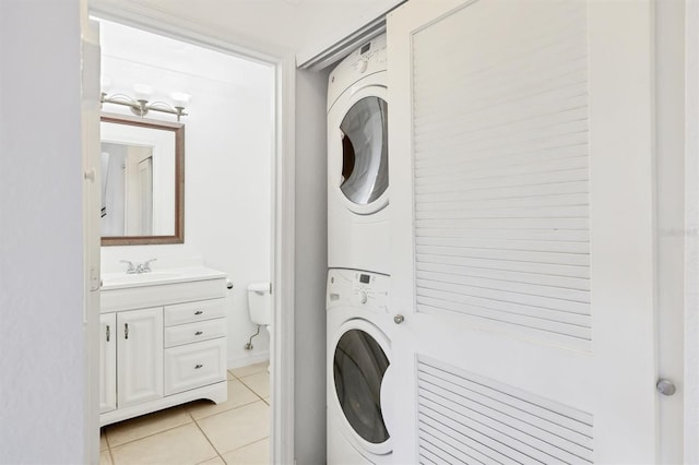 laundry area with stacked washer / drying machine, sink, and light tile patterned floors