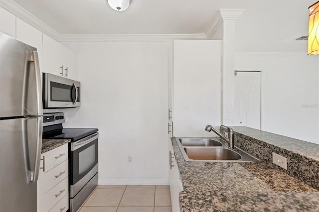 kitchen with white cabinets, light tile patterned floors, dark stone countertops, sink, and stainless steel appliances