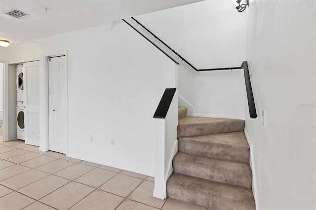 stairway with stacked washer / drying machine, ornamental molding, and tile patterned flooring