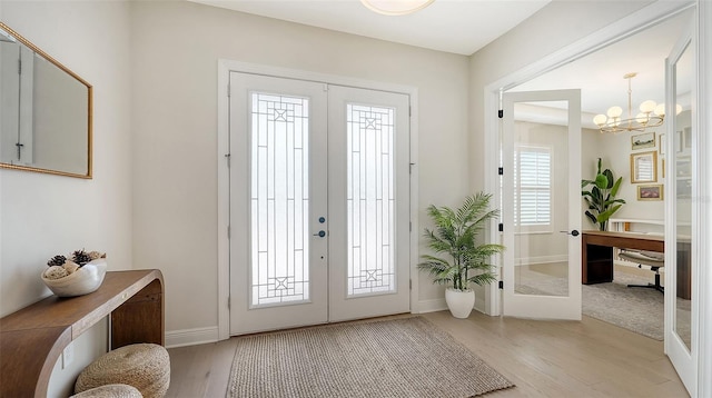 foyer entrance with french doors, light hardwood / wood-style flooring, and a chandelier