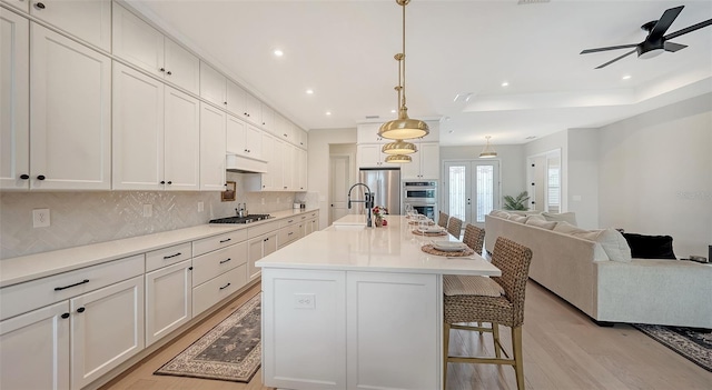 kitchen featuring a center island with sink, a kitchen breakfast bar, light wood-type flooring, stainless steel appliances, and decorative light fixtures