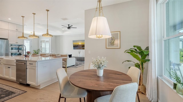 dining area with a tray ceiling, light hardwood / wood-style floors, and ceiling fan