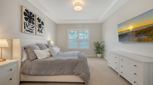 bedroom featuring light carpet and a tray ceiling