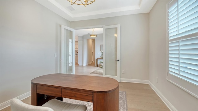 office with french doors, light wood-type flooring, and a raised ceiling