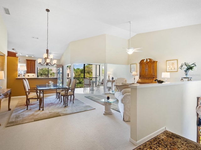 carpeted living room with ceiling fan with notable chandelier, track lighting, and high vaulted ceiling