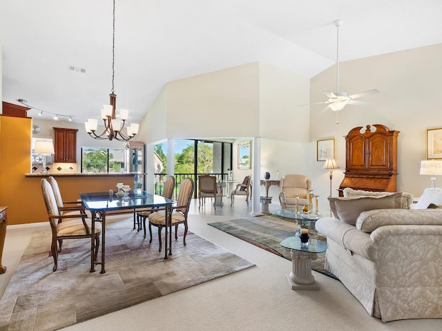 carpeted dining area with ceiling fan with notable chandelier and high vaulted ceiling