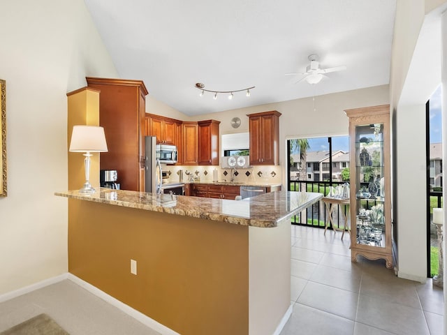 kitchen featuring appliances with stainless steel finishes, decorative backsplash, kitchen peninsula, light tile patterned floors, and lofted ceiling