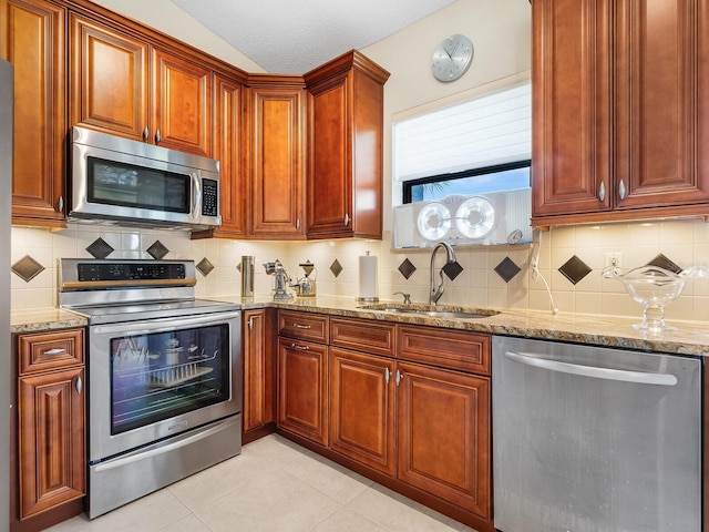 kitchen featuring appliances with stainless steel finishes, light stone countertops, light tile patterned floors, a textured ceiling, and sink