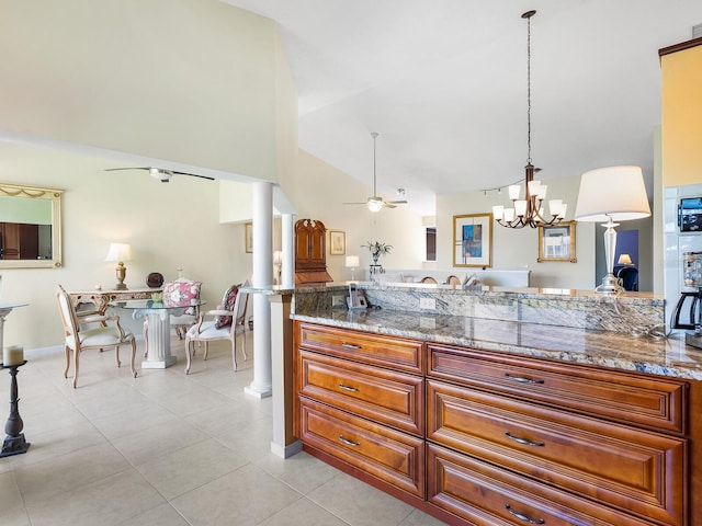 kitchen featuring light stone counters, hanging light fixtures, light tile patterned floors, ceiling fan with notable chandelier, and ornate columns