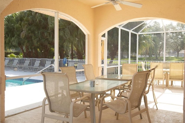 exterior space with a community pool, glass enclosure, and ceiling fan