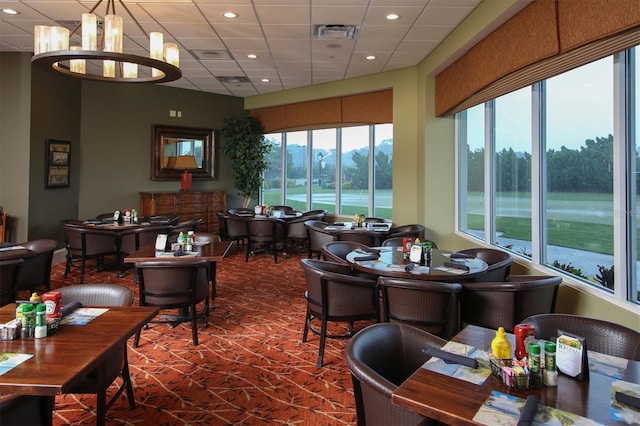 interior space featuring a water view, a drop ceiling, and a notable chandelier