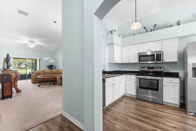 kitchen featuring dark wood-type flooring, stainless steel appliances, sink, pendant lighting, and white cabinets