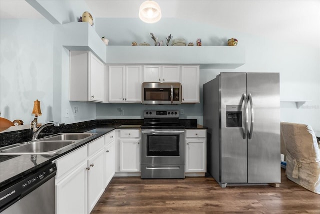 kitchen with appliances with stainless steel finishes, sink, white cabinetry, dark stone countertops, and dark hardwood / wood-style floors