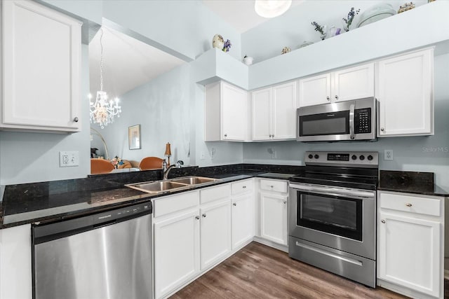 kitchen featuring dark hardwood / wood-style floors, hanging light fixtures, stainless steel appliances, sink, and white cabinetry