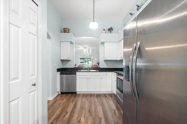 kitchen featuring appliances with stainless steel finishes, sink, white cabinetry, pendant lighting, and dark wood-type flooring